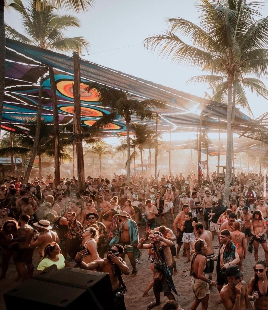 Festival Universo Paralello 2026 em Ituberá, Bahia com público dançando na praia ao pôr do sol
